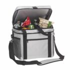 A gray and black insulated cooler bag with an open lid, filled with snacks, soda cans, a bottle, and a bag of chips. It has a shoulder strap and a front zippered pocket.