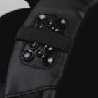 Close-up of a black fabric accessory with multiple glossy black round buttons arranged on it. The textured material and stitching details are visible, giving a sense of its surface and design.