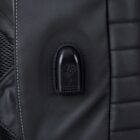 Close-up of a black bag showing a USB charging port on its exterior. The texture of the bag includes stitched vertical lines and a mesh side pocket nearby.
