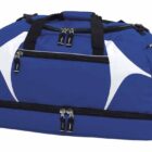 A large blue sports duffel bag with black handles and straps. It features white geometric patterns on the sides and multiple zippered compartments, including a large main section and a separate bottom compartment.