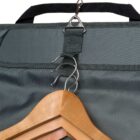 Close-up of a green garment bag with a wooden hanger partially visible. The hanger is attached to the bag with metal hooks, and the bag has a black handle. The fabric of the bag appears sturdy and durable.