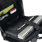 Open backpack revealing a laptop, tablet, and various accessories such as a red power bank and cables in dedicated compartments. The interior is organized with straps and pockets, emphasizing travel or tech readiness.