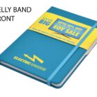 A blue notebook with a yellow band around it, displaying the text Save Big and Up to 50% off for an EOY Sale. The notebook has an Electric Kingdom logo and an attached blue elastic band.