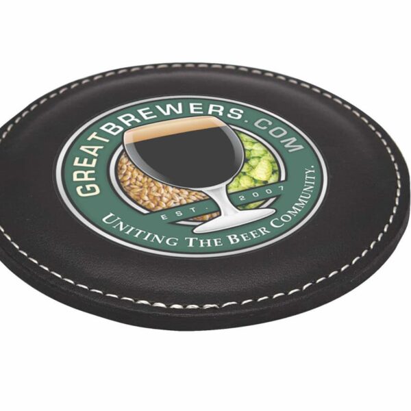 A round, black coaster with white stitching displays the logo for Greatbrewers.com. A glass filled with liquid and images of grain and hops are in the center. The text reads Uniting the Beer Community and Est. 2007.
