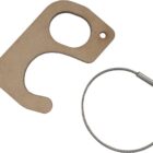 A beige no-touch tool made from a flat material, with a hook and circular opening, lies next to a silver wire keychain loop. The tool is designed for hygienic use on door handles and buttons.