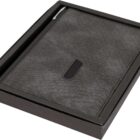 A gray fabric-covered notebook with a black accent is presented in a black box. A silver pen is attached to the notebook.