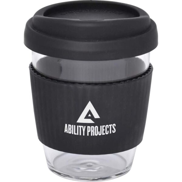 A transparent glass cup with a black silicone lid and grip. The grip has the Ability Projects logo printed in white, featuring a stylized triangle design.