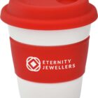 A white reusable coffee cup with a red silicone lid and grip shows the logo of Eternity Jewellers.