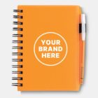 Orange spiral notebook with Your Brand Here in a white circle on the cover. A pen is attached on the right side.