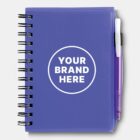 A purple spiral-bound notebook with YOUR BRAND HERE in white text inside a circle on the cover. A purple pen is clipped to the right side of the notebook.
