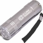 Close-up of a silver flashlight with C-Link Agency printed on the side. It has a black wrist strap and features multiple LED lights at the front.