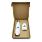 Open brown cardboard box containing a white insulated bottle and a white tumbler, both with a blue logo on them. The bottle has a silver cap. Items are neatly placed side by side.