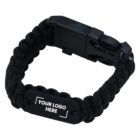 Black paracord survival bracelet with a black plastic buckle. A metal plate on the bracelet displays the text YOUR LOGO HERE in white.
