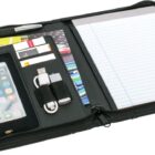 An open black organizer showcasing a notepad, pen, smartphone, credit cards, and a USB cable, neatly arranged within designated compartments.