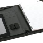 A black zippered portfolio folder is open, showing a lined spiral notebook on the right side. The left side has pockets for cards and a holder for a tablet or e-reader.