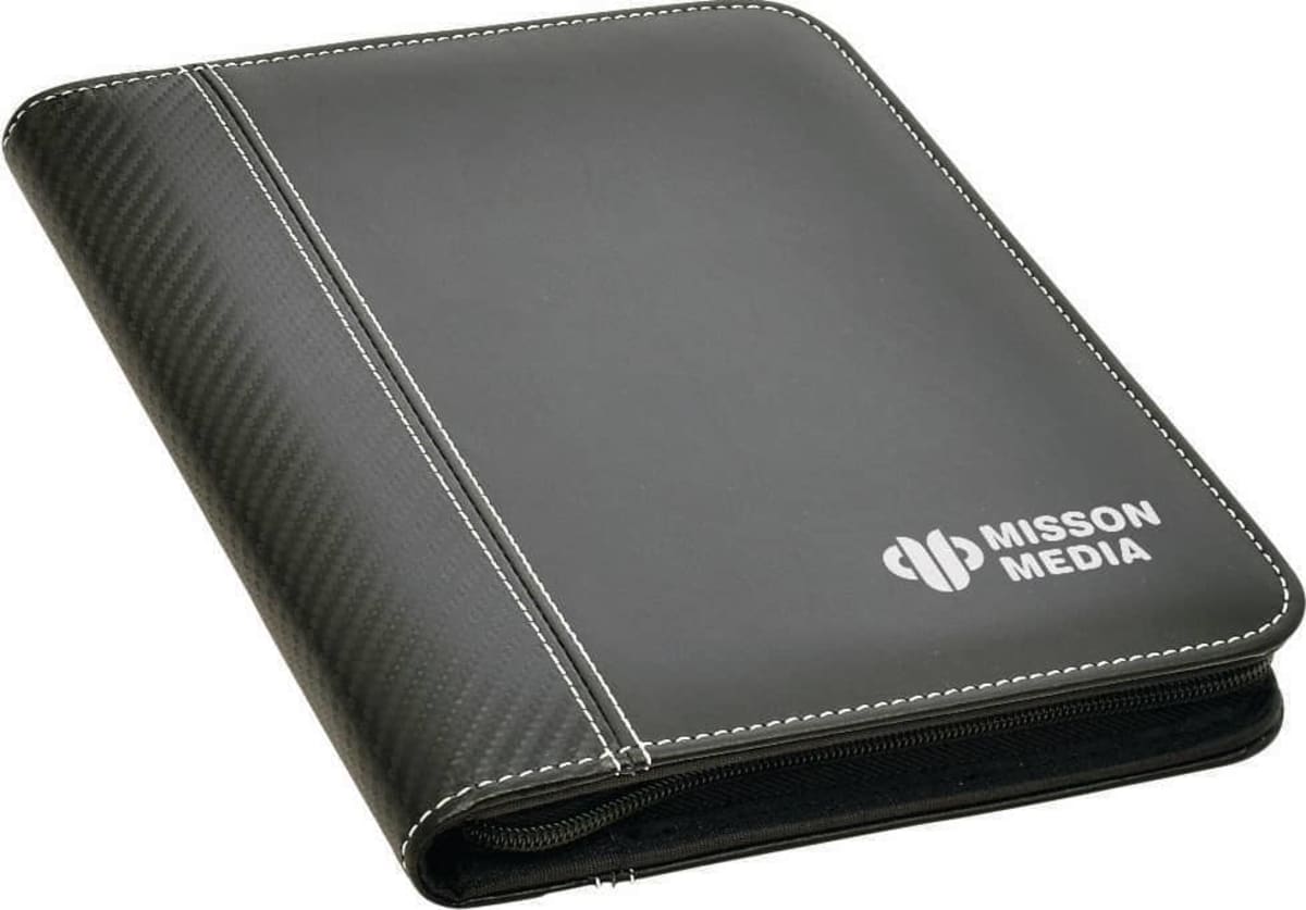 A black zippered binder with white stitching features the Mission Media logo in white on the front cover. The binder has a faux leather and fabric design, offering a sleek, professional appearance.