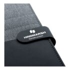 Close-up of a gray and black fabric folder featuring a strap with HINDMARSH Construction printed in white. The fabric has a textured appearance, contrasting with the smooth black material.