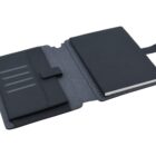 Open black notebook with a matching cover and a flap closure. The interior has multiple card slots on the left side, and a lined notebook is on the right. The cover material appears to be a textured fabric.