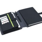 Open black notebook case with multiple compartments. Holds business cards, a white tablet, and a black notebook. A pen is placed in the center. The exterior is a dark fabric material, and the design appears sleek and organized.