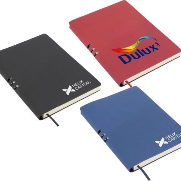 Three notebooks are displayed: one black and one blue, both featuring the Helix Capital logo, and a red one with the Dulux logo. They are arranged in a triangular formation on a white background.