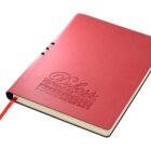 A red notebook with Deluxe The Premier Option embossed on the cover. It features a ribbon bookmark and rounded edges, providing a sleek and elegant appearance.