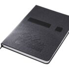 A closed dark gray notebook with Bliss and Live the Process embossed on the cover. It has an elastic strap and a ribbon bookmark. The notebooks texture looks fabric-like.