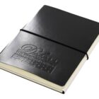 A closed black leather notebook with an elastic strap and embossed text reading Deluxe The Premier Option on the cover. The edges of the cream-colored pages are visible.