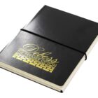 A black leather-bound notebook with a gold foil stamp on the cover reading Deboss The Premier Option and a brick pattern beneath the text. It is secured with a black elastic band around the middle.