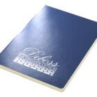 A closed blue notebook with Deboss The Premier Option printed in white on the cover, featuring a decorative design and brick pattern. The edges of the pages are visible, showcasing a clean and minimalist design.