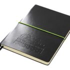 A closed black leather-bound notebook with an embossed logo and the text, The Premier Option on the cover. It has a green elastic band wrapped around it horizontally and a black ribbon bookmark peeking out from the bottom.