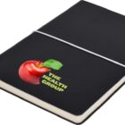A black notebook with a white elastic band and a ribbon bookmark. The cover features an illustration of a red apple with a green leaf and the text The Health Group below the apple.