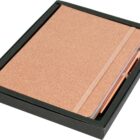 A closed, glittery rose gold notebook is placed in a black box, accompanied by a matching rose gold pen. The notebook features an elastic band closure.