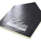 A black journal with a pentagonal shape, featuring the words Delbys: The Premier Option in white script on the cover. The book is closed and positioned against a white background.