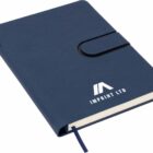A blue, hard-cover notebook with a pen loop and strap closure sits closed. IMPRINT LTD is printed in white on the front cover. A matching blue ribbon bookmark is visible at the bottom.