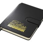 A black notebook with a textured cover, featuring gold embossed text Deloss The Premier Option and a logo. It has a strap closure and a ribbon bookmark.