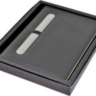 A black gift box containing a sleek, black textured notebook with a pen attached. The pen is secured by an elastic band inside the box.