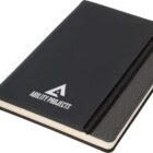 A black notebook with ABILITY PROJECTS written in white on the cover. It features a textured black spine and a zippered pocket on the front. A black ribbon bookmark is also visible.