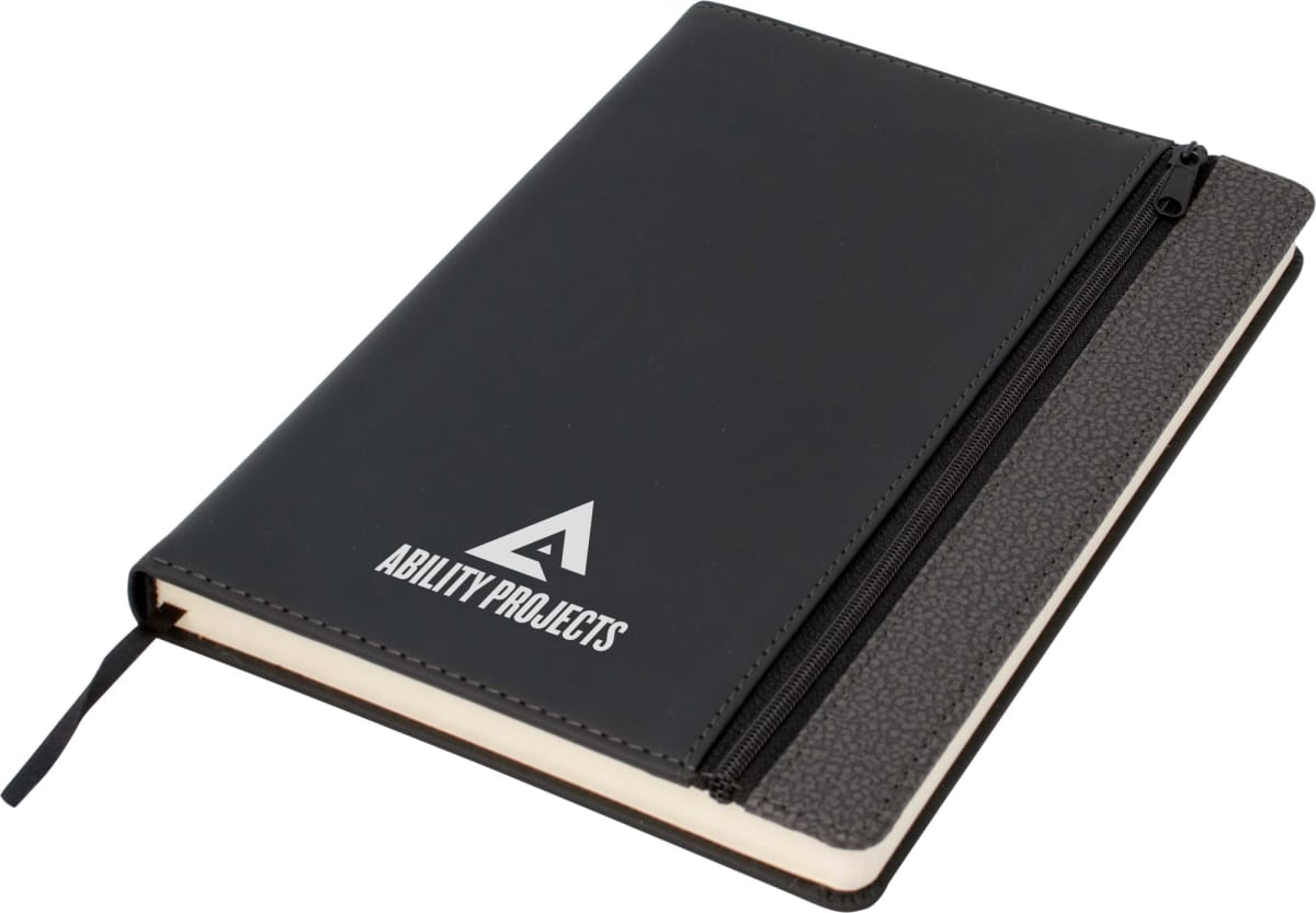 A black notebook with ABILITY PROJECTS written in white on the cover. It features a textured black spine and a zippered pocket on the front. A black ribbon bookmark is also visible.