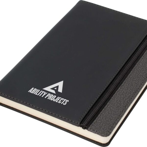 A black notebook featuring the Ability Projects logo on the front cover. The notebook has a zipper pocket on one side and a black ribbon bookmark.