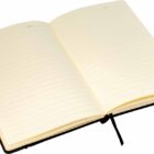 An open, cream-colored notebook with lined pages and a black ribbon bookmark. The notebook lies flat, revealing its blank sheets ready for writing.