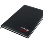 A black notebook with a ribbon bookmark. The cover features the Cisco logo in red and white at the bottom right corner.