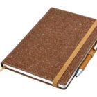 A brown hardcover notebook with a textured finish lies closed. An elastic band wraps around it horizontally, securing a pen on the side. A ribbon bookmark is visible, extending from the bottom.