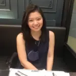 Smiling at the table, mask hanging, ready to Meet the Team.
