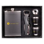 A gift set featuring a flask with the GOLDEN BAR logo, two metal shot glasses, a bottle opener with a corkscrew, and a funnel, all neatly arranged in a box.