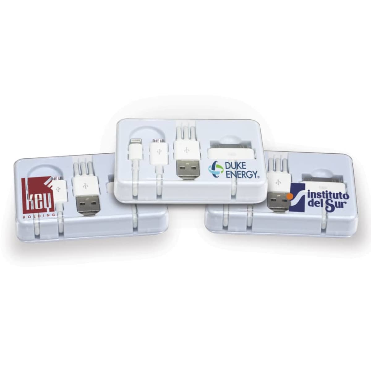 Three white multi-adapter charging sets in transparent cases, each featuring different logos: Key Holdings on the left, Duke Energy in the center, and Instituto del Sur on the right.