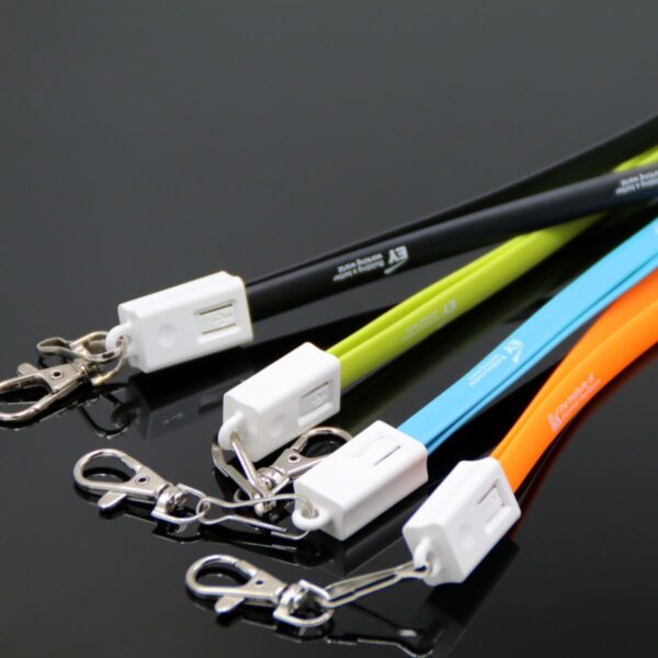 A set of USB charging cables in black, green, blue, and orange, each with a metal clasp and a white connector. The cables are neatly arranged on a glossy black surface.