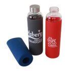 Two glass bottles with silicone sleeves and metal lids. One sleeve is black with white text and the other is red with a white logo. A blue sleeve is lying on the side.
