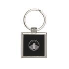 A square metal keychain with a black center featuring a white logo. The logo depicts a needle encircled by five stars. The keyring is attached at the top.