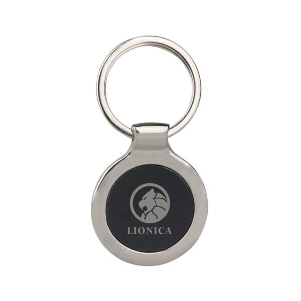 A round metal keychain with a black center featuring a silver lion emblem and the word LIONICA beneath it.
