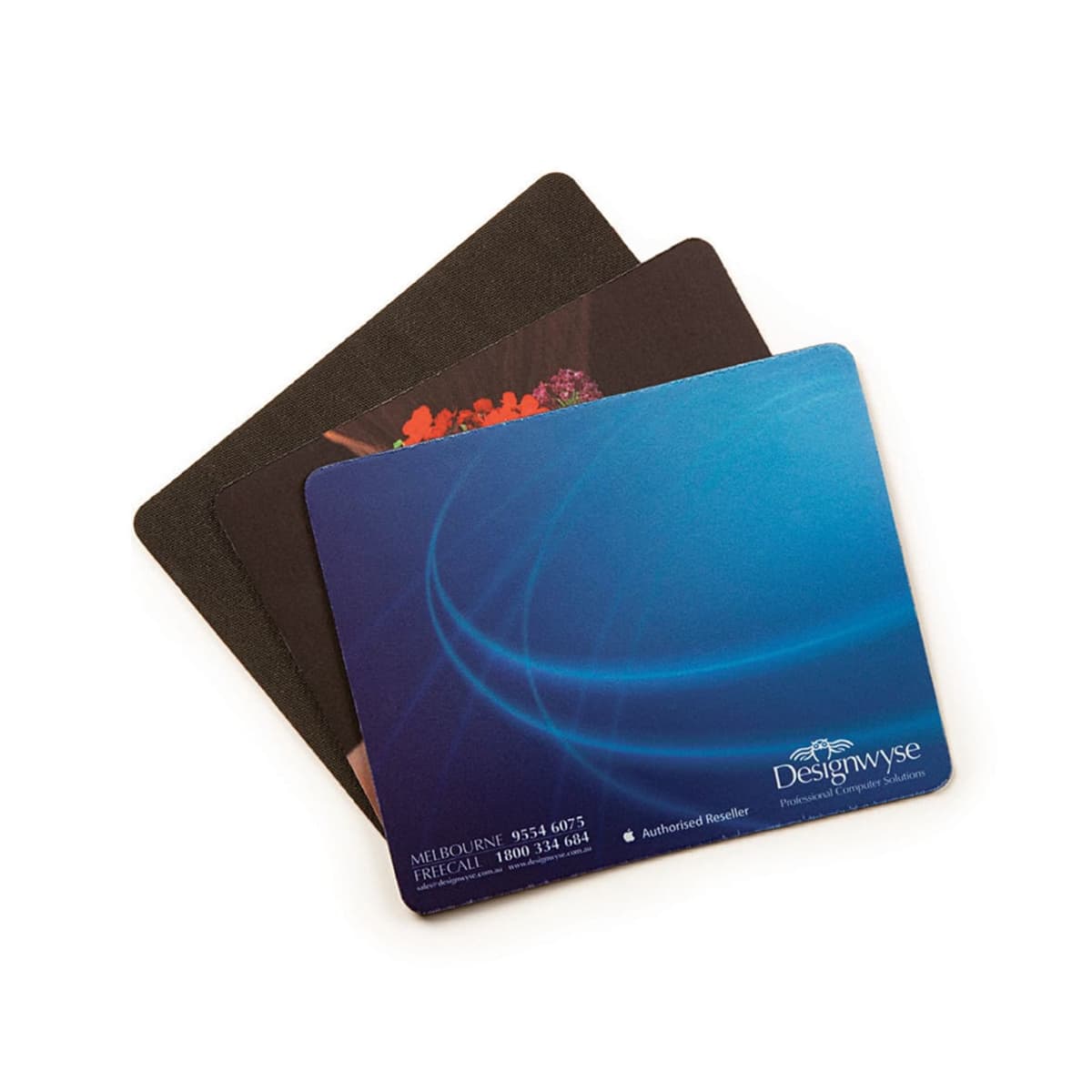 Three stacked mouse pads, the top one blue with white swirls and Designwyse logo. The middle pad shows a floral design. The bottom pad is plain black.